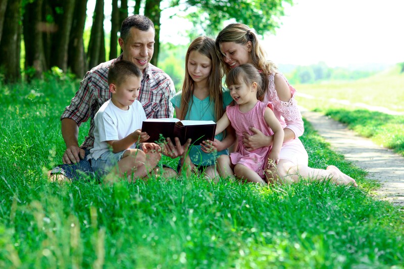 A young family studies the bible together.