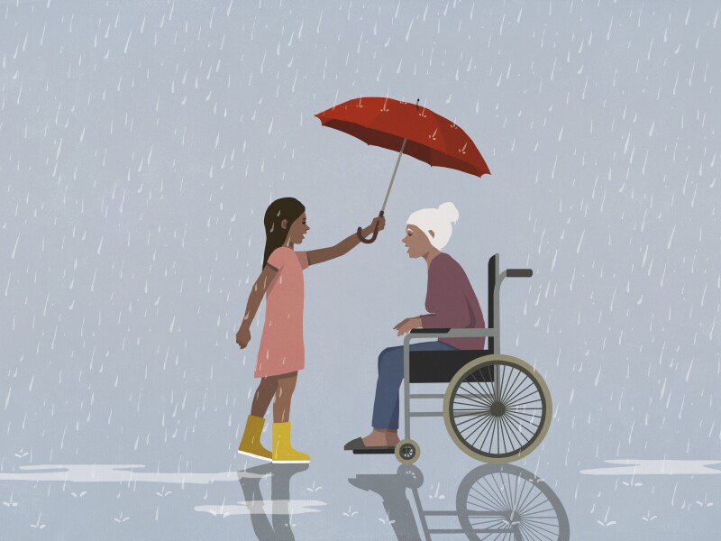 Caring girl holding umbrella over senior woman in wheelchair, protecting her from rain