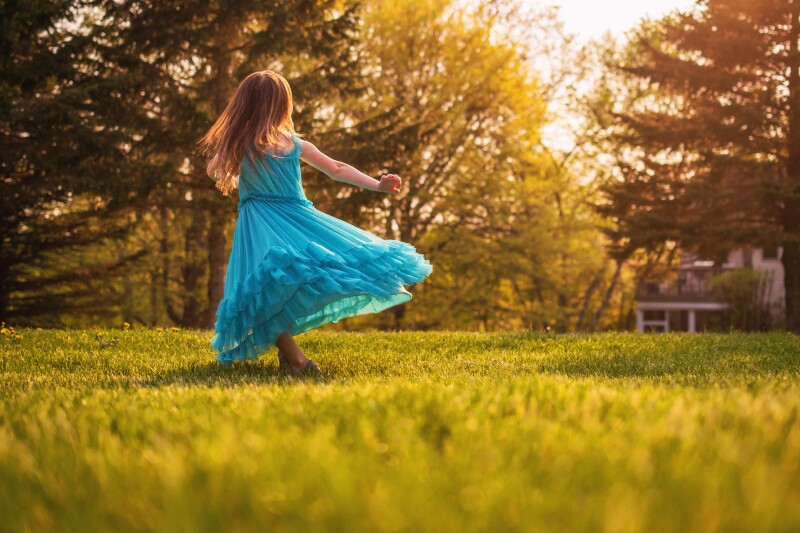 Girl in garden spinning around in a dress