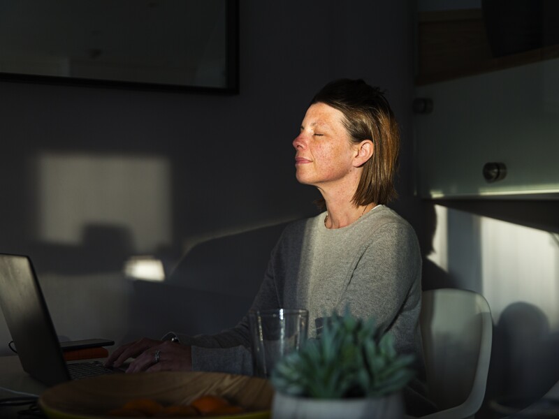 Woman closing her eyes as the last sun rays of the day come into her house