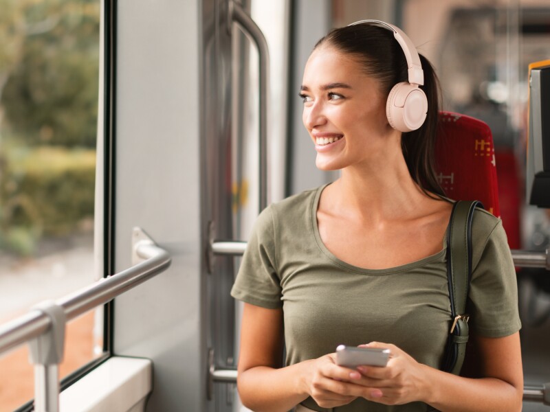 Lady Sitting Wearing Headphones Listening Music Via Phone In Tram