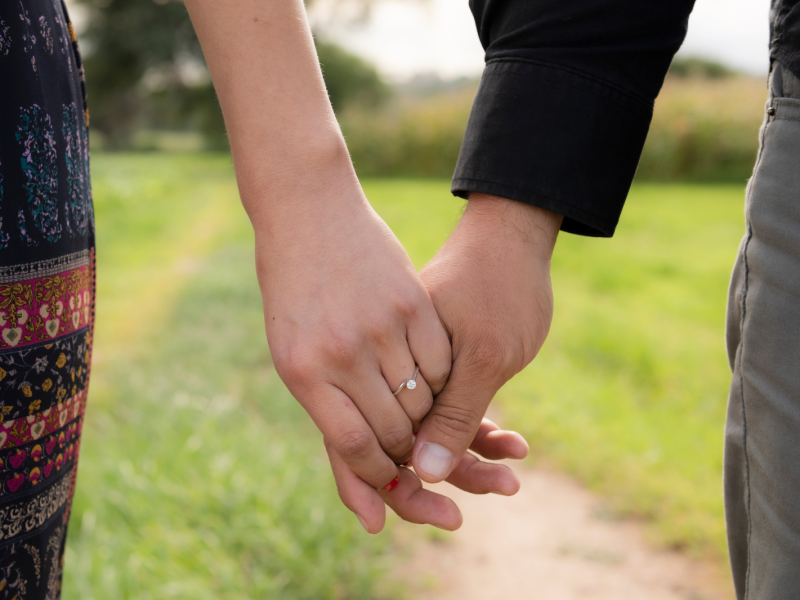 An engaged couple holds hands.