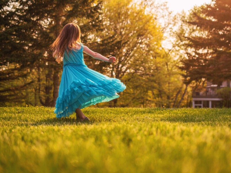 Girl in garden spinning around in a dress