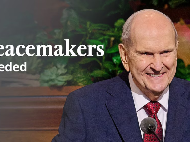 Russell M. Nelson smiles at a pulpit. Text overlaying the image says “Peacemakers Needed” with a logo from The Church of Jesus Christ of Latter-day Saints.